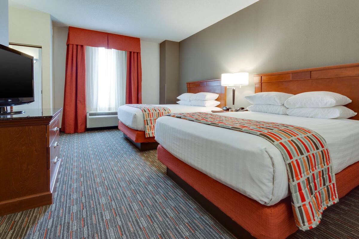 Une chambre d’hôtel avec deux lits, une télévision et un bureau.