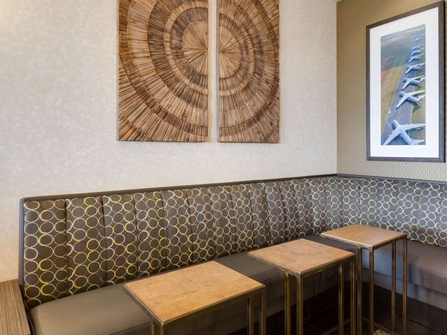 Ein modernes Interieur mit Wandmuster, einer Sitzecke mit Tischen und einem gerahmten Bild an der Wand.