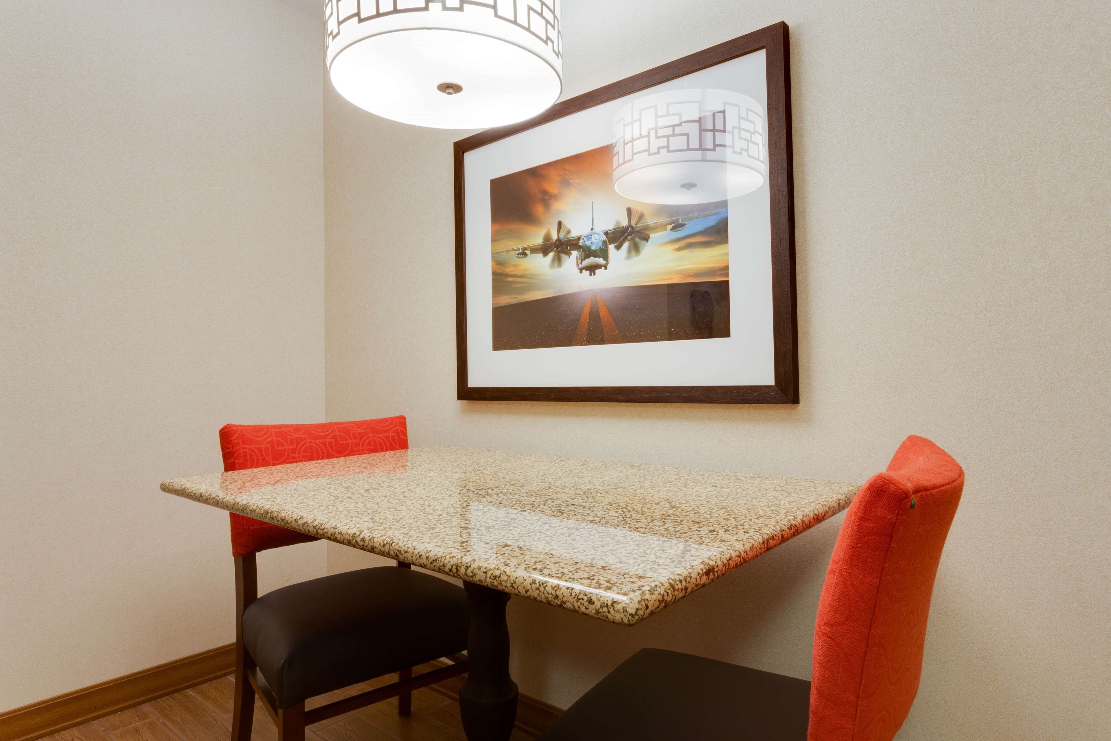 Un coin repas avec une table et des chaises, un tableau encadré au mur et un luminaire suspendu.
