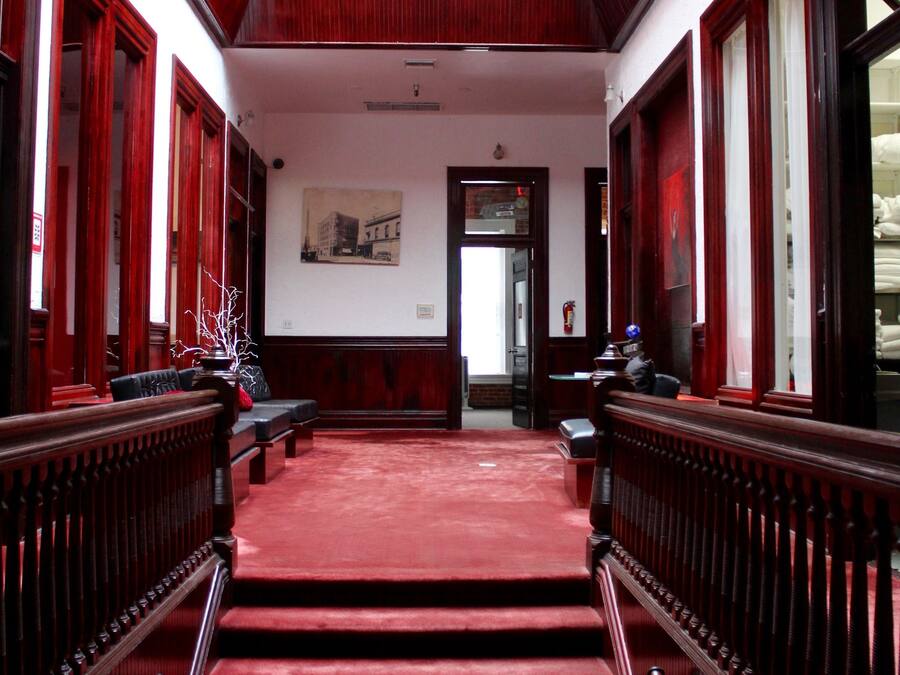 A grand staircase with a red carpet leading to a high ceiling with a skylight.