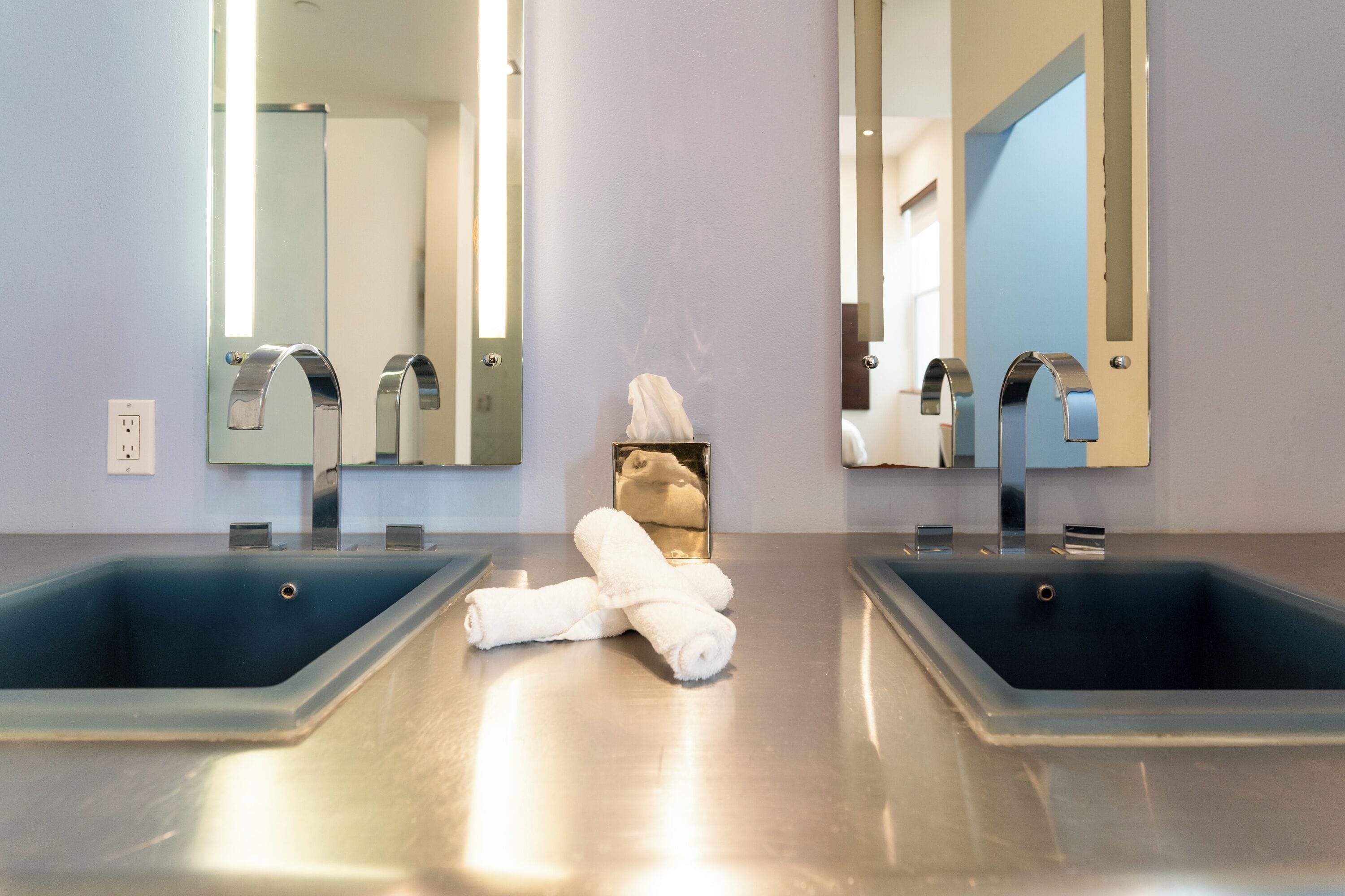 Une salle de bain avec deux lavabos, une serviette et un miroir.