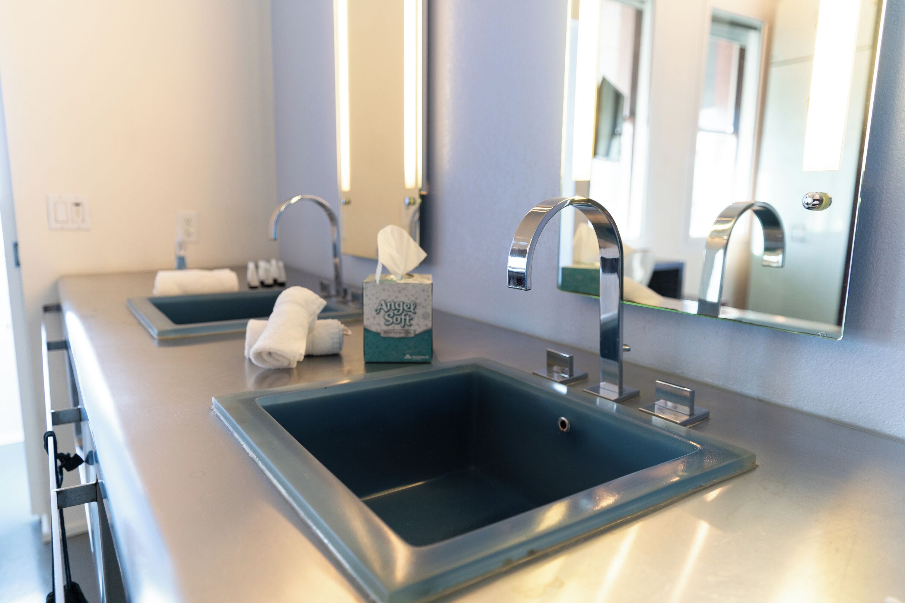 Ein modernes Badezimmer mit zwei Waschbecken, einem Spiegel und einem Handtuchhalter.