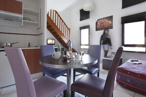 Una cocina moderna con comedor, una escalera y un ventanal grande.
