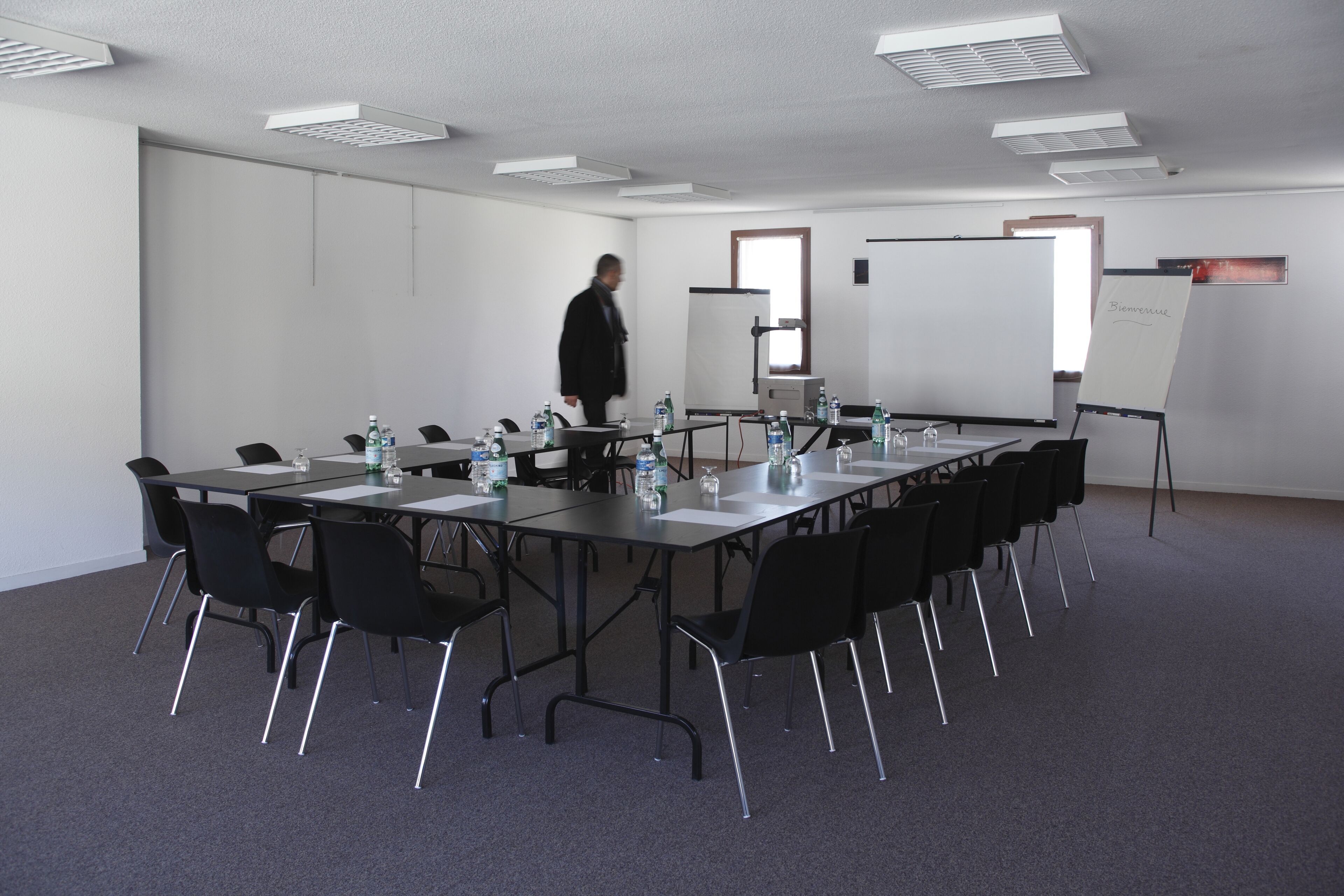 A conference room with a long table, chairs, water bottles, and a whiteboard.