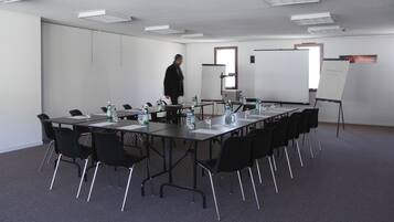 A conference room with a long table, chairs, water bottles, and a whiteboard.