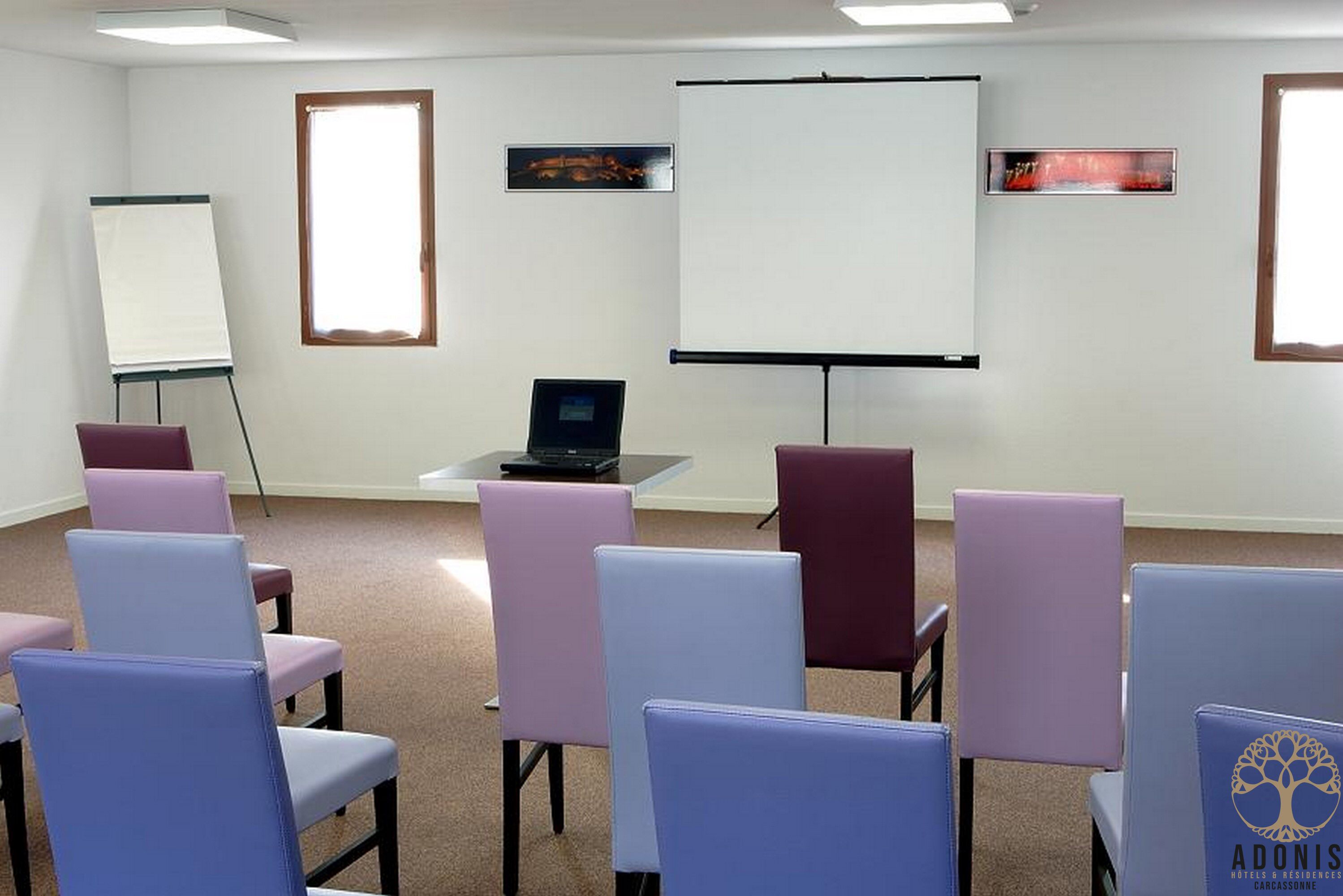 A conference room with a whiteboard, projector, and a laptop on a table.