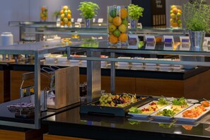 Un buffet proposant une variété de plats, notamment des fruits, des légumes et des salades.