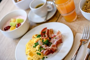 A breakfast setting with scrambled eggs, bacon, and a fruit bowl. - Hilton Garden Inn Stuttgart Neckar Park (Stuttgart)