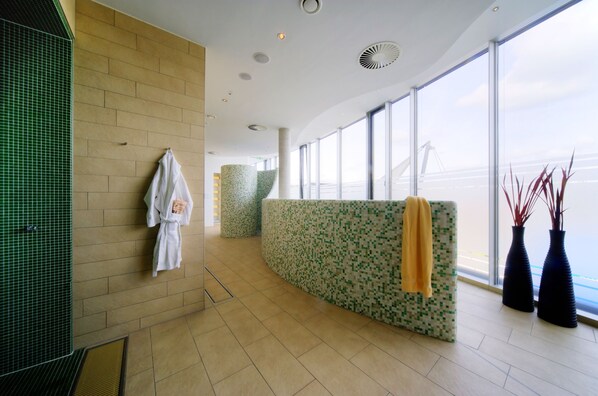 A modern hotel lobby with a reception desk, a green-tiled wall, and large windows offering a view of the sky. - Hilton Garden Inn Stuttgart Neckar Park (Stuttgart)
