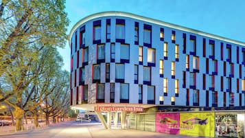 A modern hotel building with a curved facade, large windows, and a visible entrance.