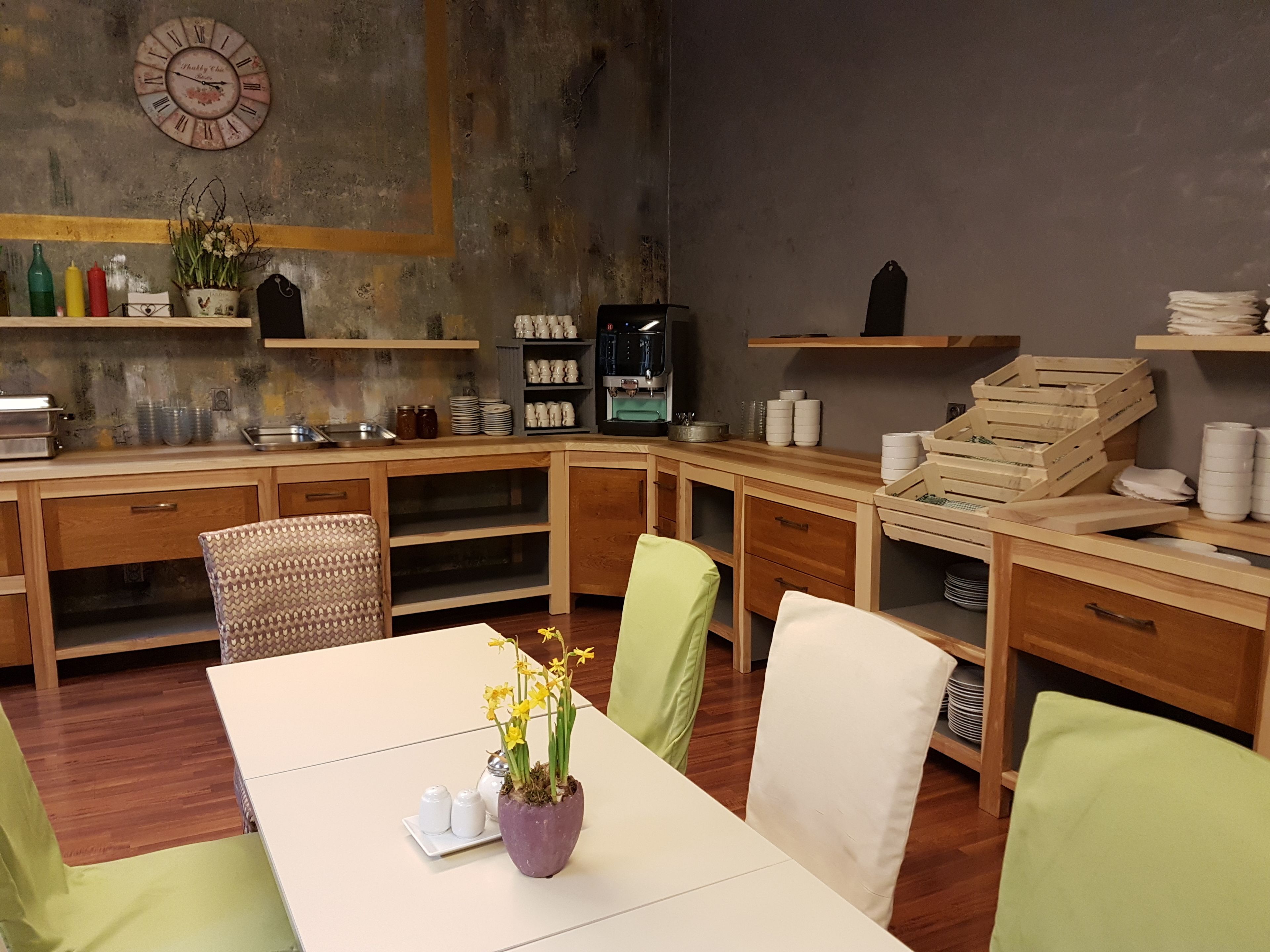 A cozy kitchen with wooden cabinets, a coffee machine, and a clock on the wall.