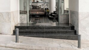 L'ingresso di un hotel dal design moderno, con una porta in vetro, una zona reception con un divano e il numero '3' ben visibile sulla parete.