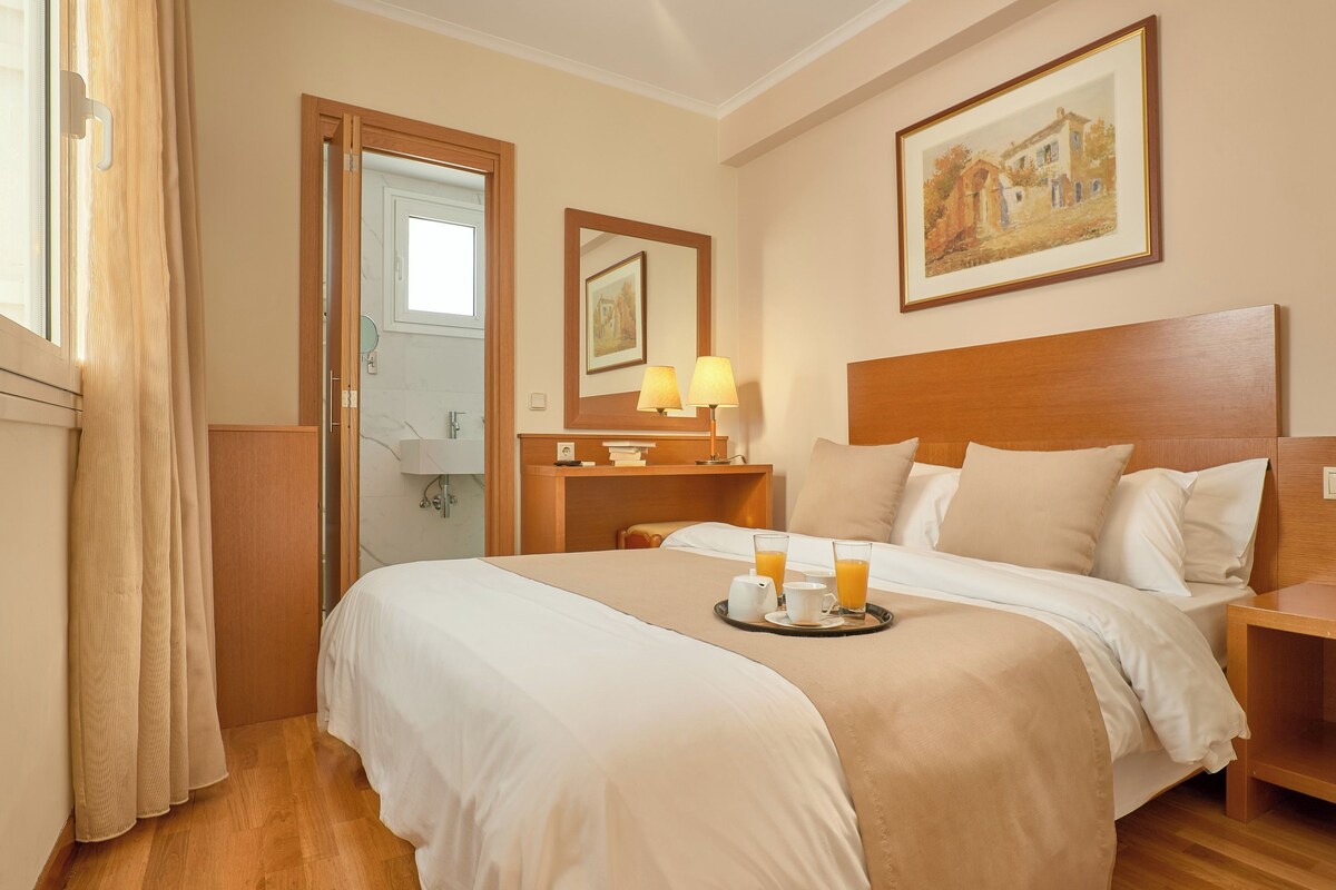 A hotel room with a bed, bedside table, and a painting on the wall.