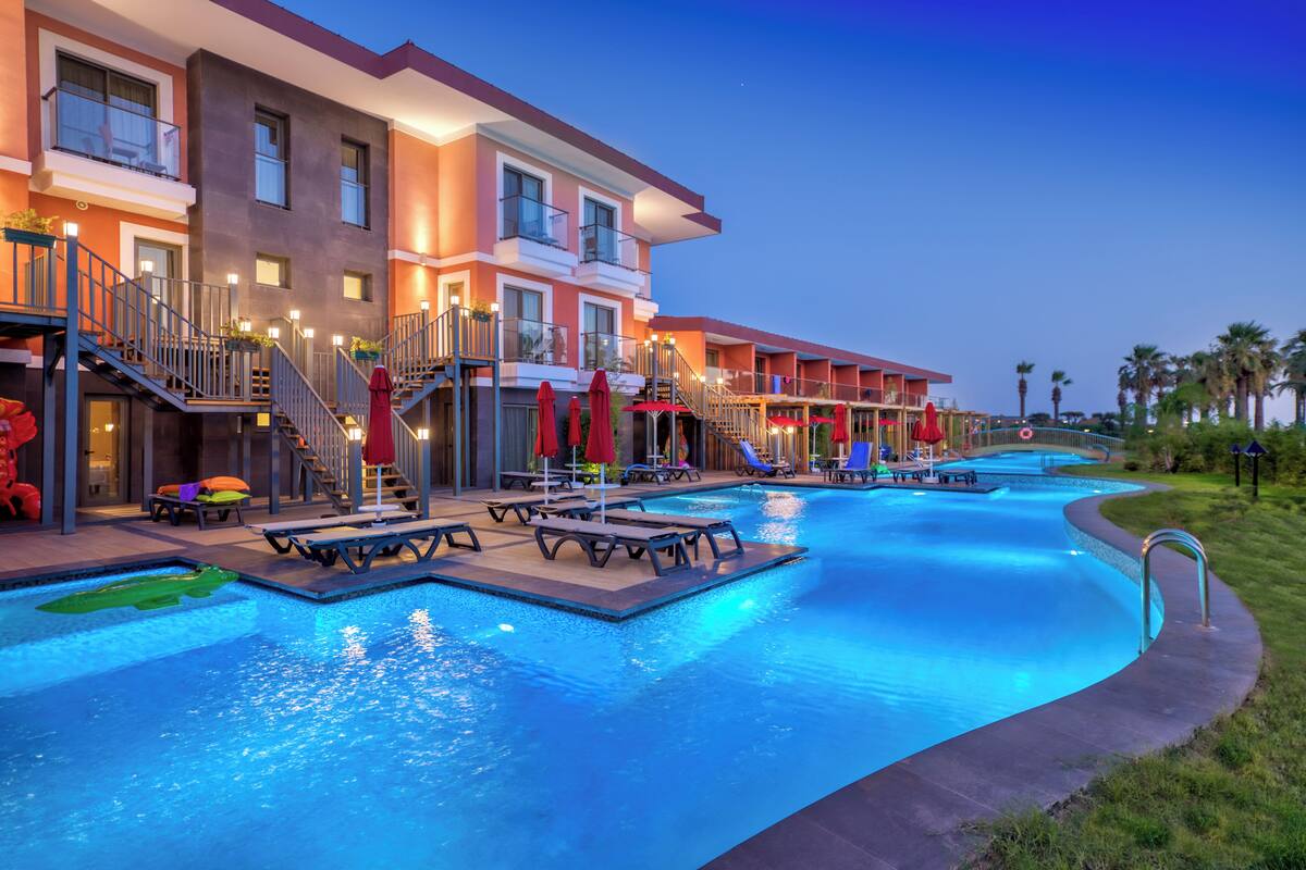 A hotel with a swimming pool, multiple balconies, and outdoor seating areas.