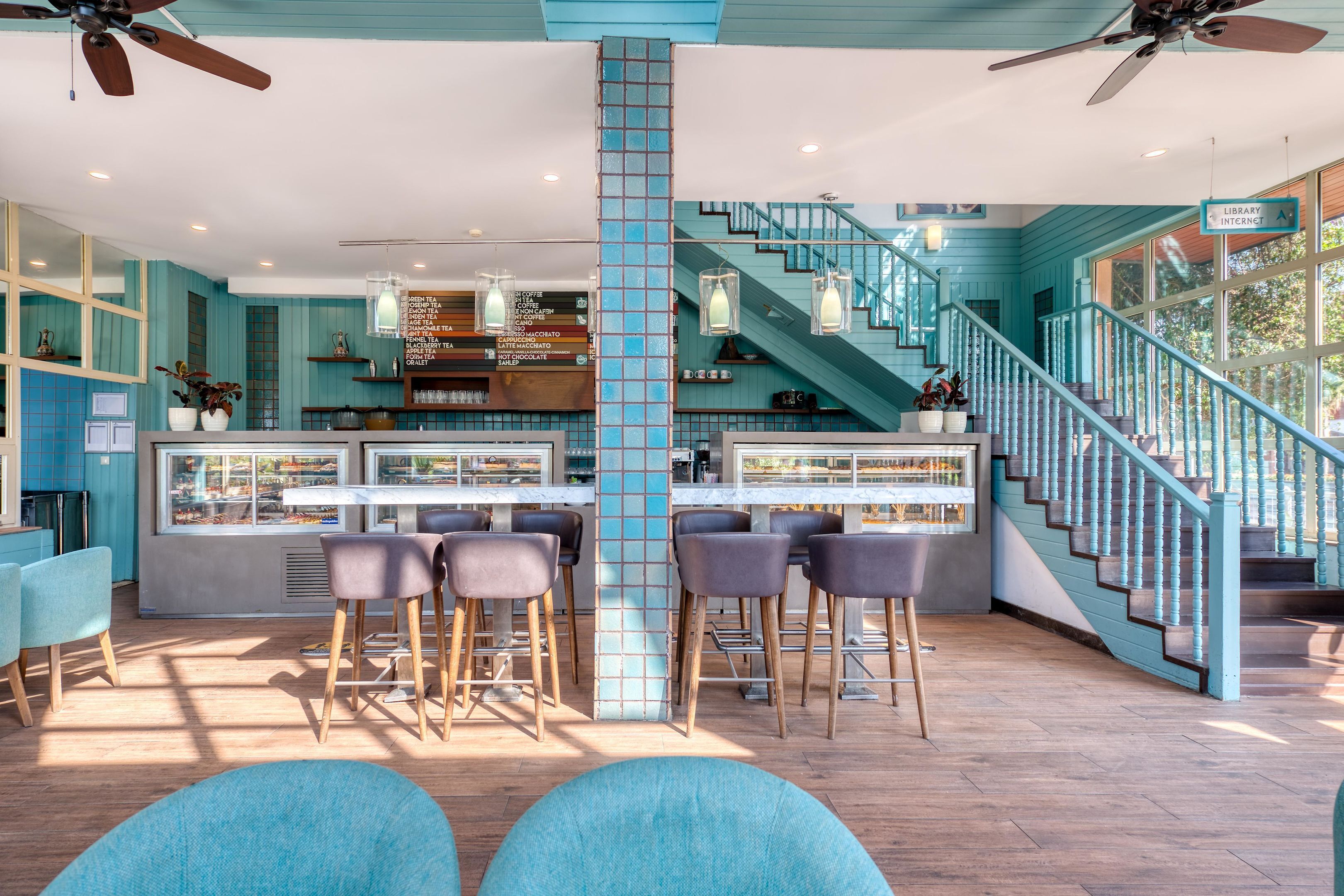 A bar area with stools, a staircase, and a view of the outside.