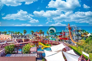 A water park with slides and pools, surrounded by palm trees and a view of the ocean.