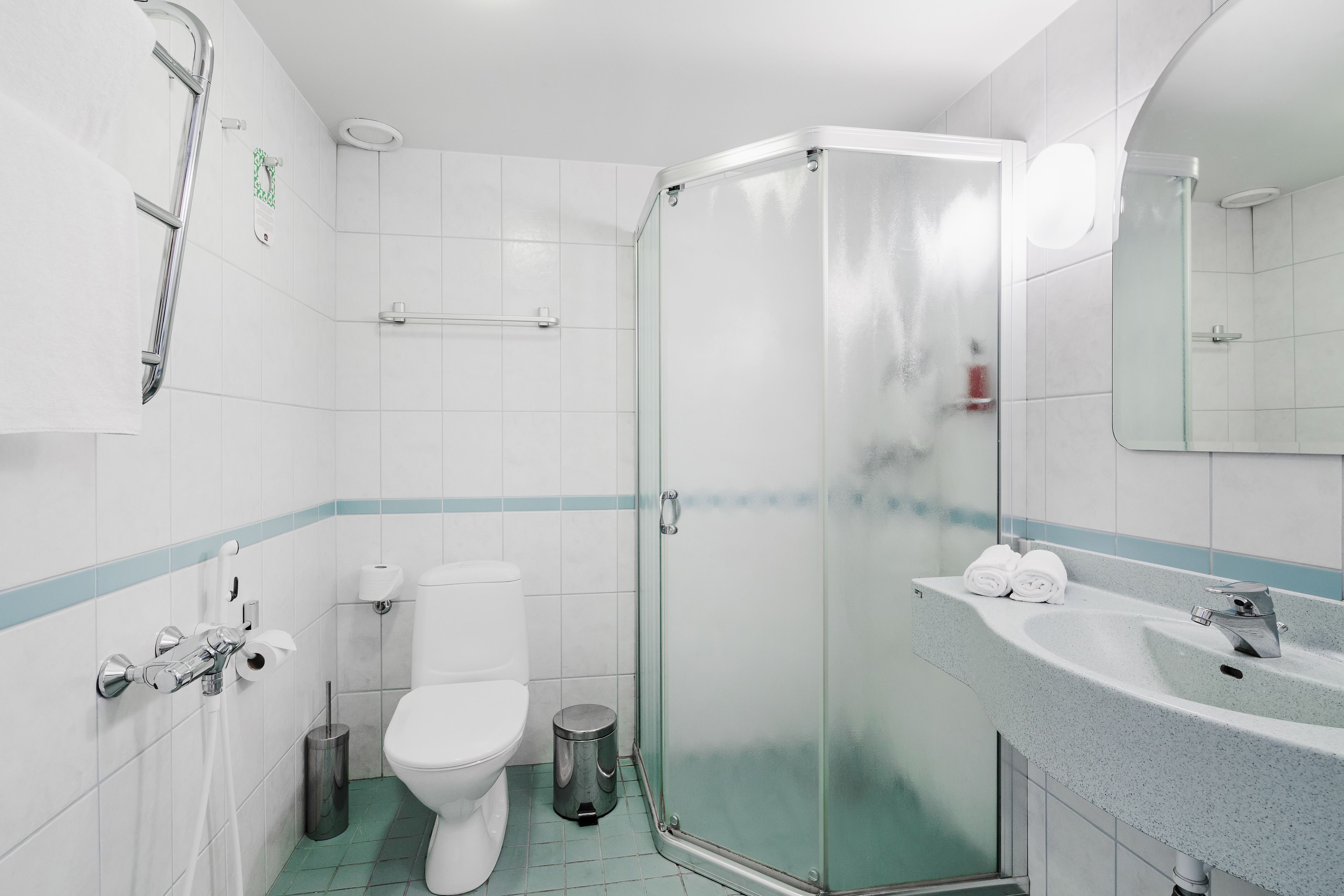 Un baño moderno con cabina de ducha de vidrio, inodoro blanco y lavabo con espejo.