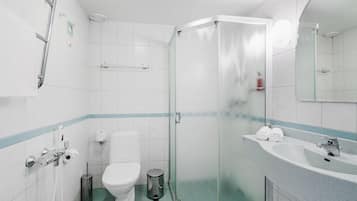 Un baño moderno con cabina de ducha de vidrio, inodoro blanco y lavabo con espejo.