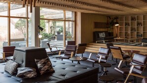 A modern lounge with a wooden ceiling, leather seating, and a view of the outdoors. - Hotel Rantapuisto (Helsinki)