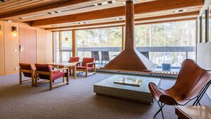 A modern interior with wooden beams, a large fireplace, and seating areas. - Hotel Rantapuisto (Helsinki)