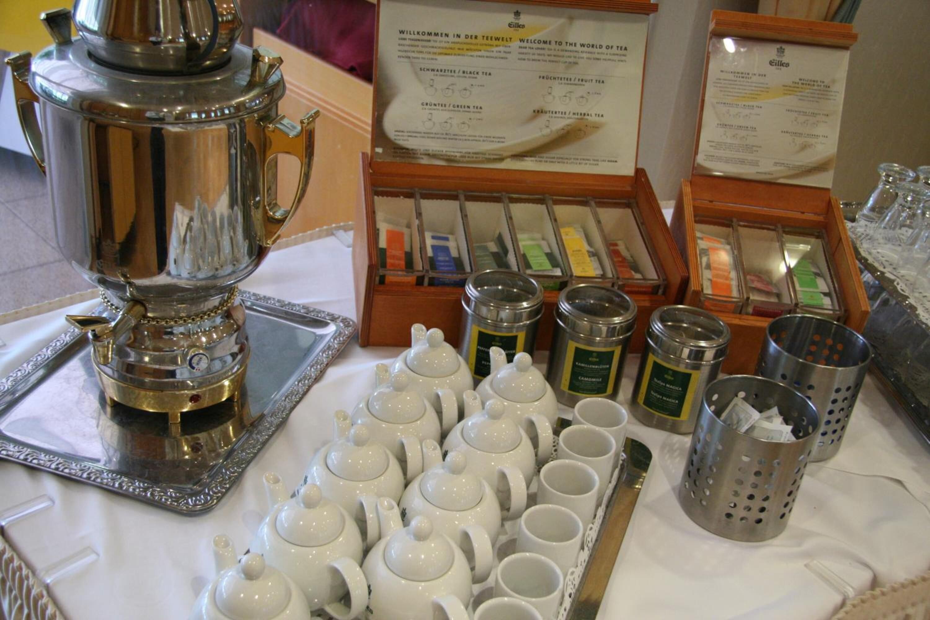 Un juego de té dispuesto con varias teteras, tazas y latas de té sobre una mesa.