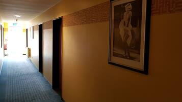 Un pasillo con puertas, papel tapiz estampado y un cuadro en la pared.