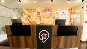 A reception desk with a wooden finish and a logo, situated in a lobby with a map mural in the background.