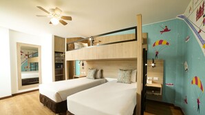 A room with two bunk beds, a ceiling fan, a desk with a chair, and a wall with colorful murals.