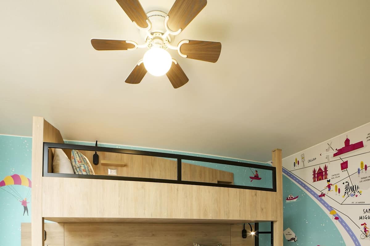 Ein Schlafraum mit Etagenbett, Deckenventilator, zwei Betten und einer Wand mit farbenfrohen Wandgemälden.