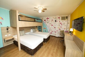 Habitación de hotel pequeña con una cama litera, un escritorio con lámpara, una silla y un mapa en la pared.