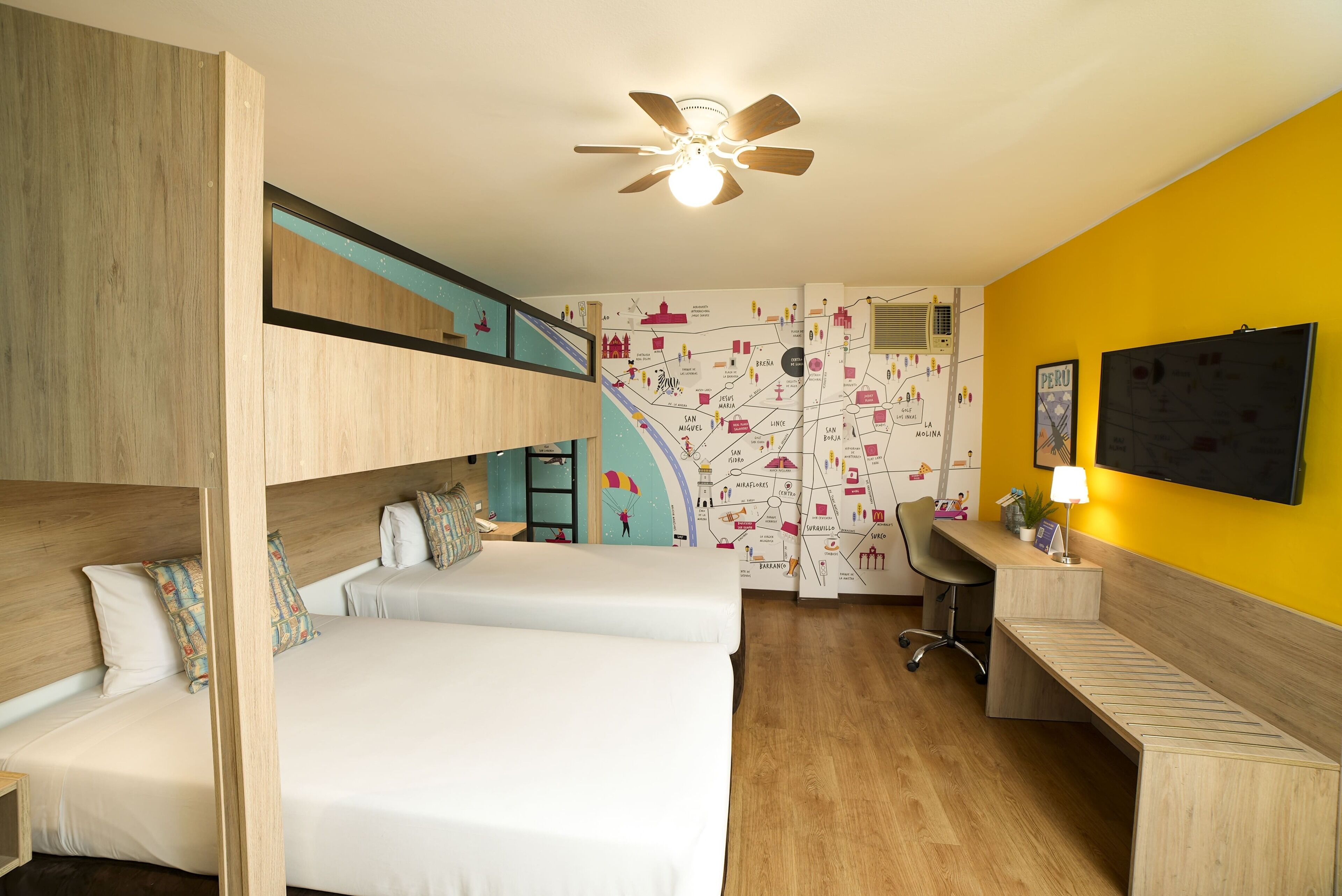 A room with bunk beds, a desk, a chair, a ceiling fan, and a wall with a map.