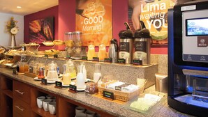 A breakfast buffet area with various food items and a coffee machine.