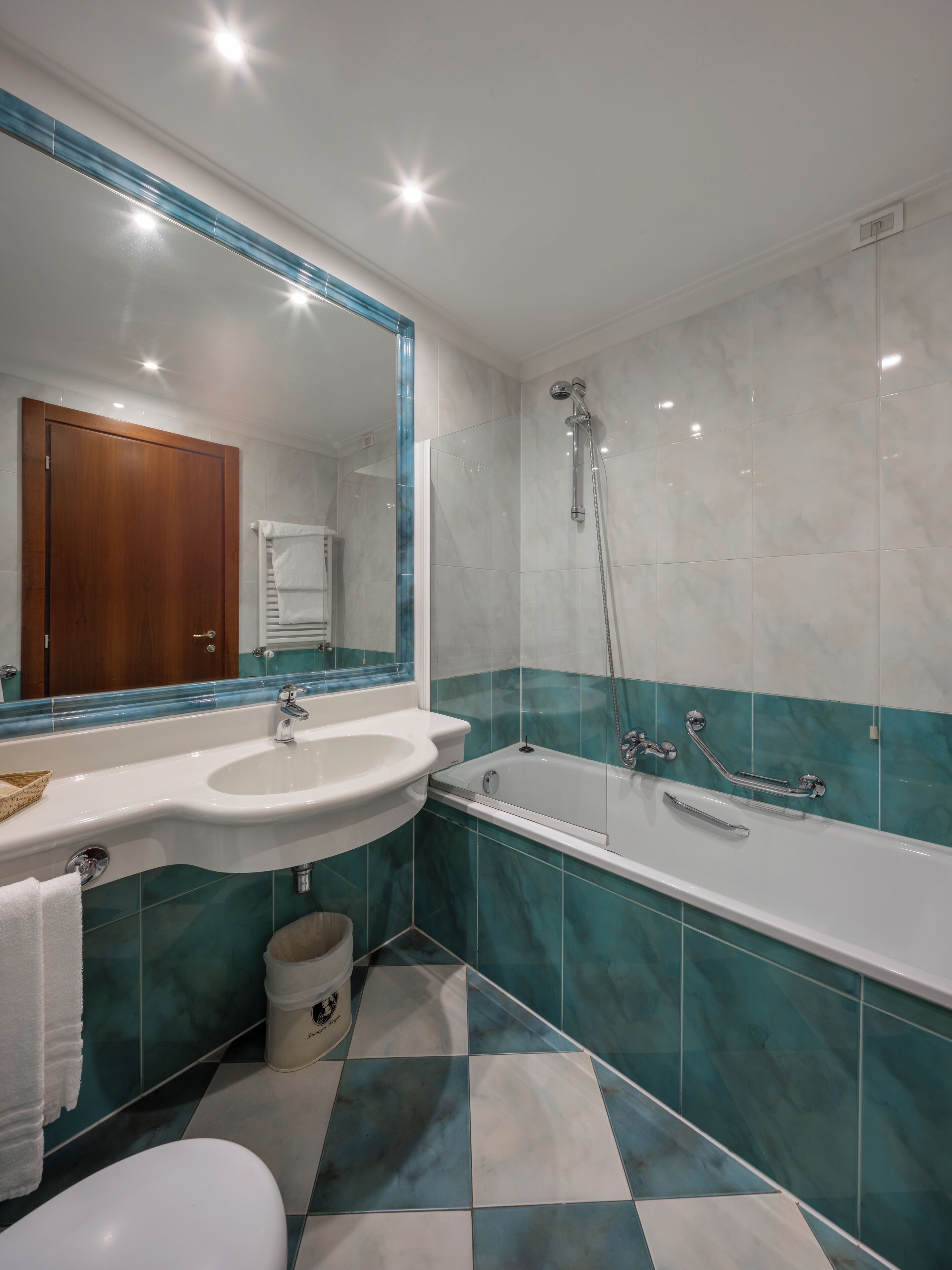 Une salle de bain équipée d’un lavabo, d’un miroir, d’une baignoire et de toilettes.