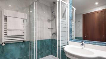 A modern bathroom with a glass-enclosed shower, a white sink, and a wooden cabinet.