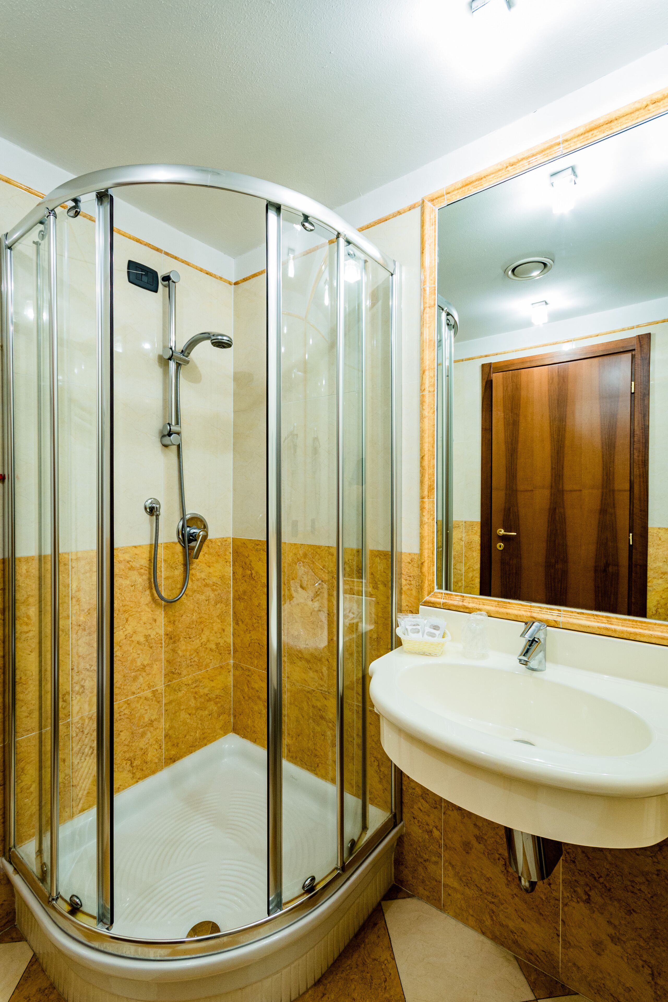 Cabina doccia con porta in vetro e lavandino con specchio sopra.