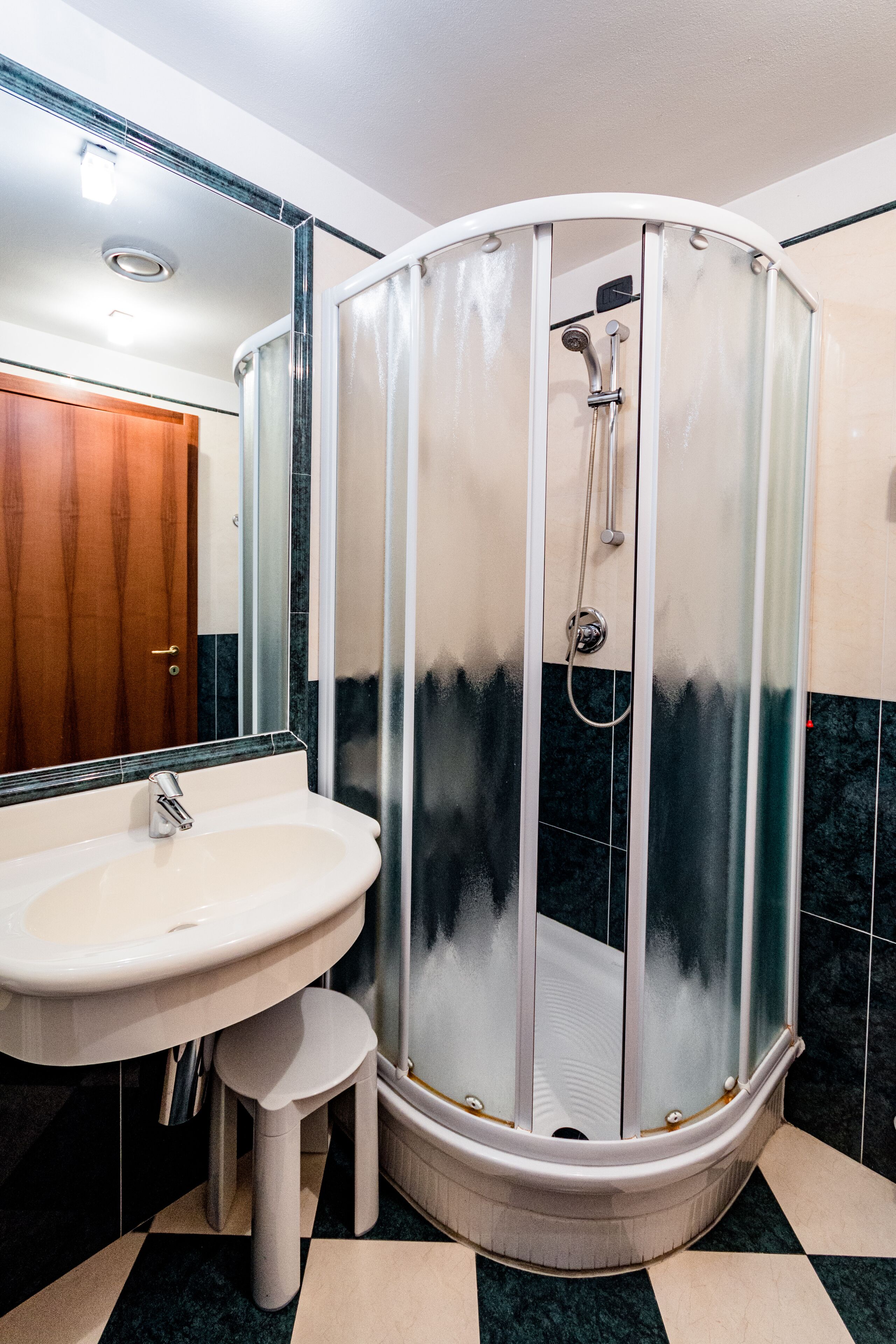 A bathroom with a glass-enclosed shower, a sink, and a mirror.