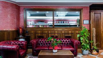 A red leather sofa, a wooden coffee table, and a large window with a view of a bar area.