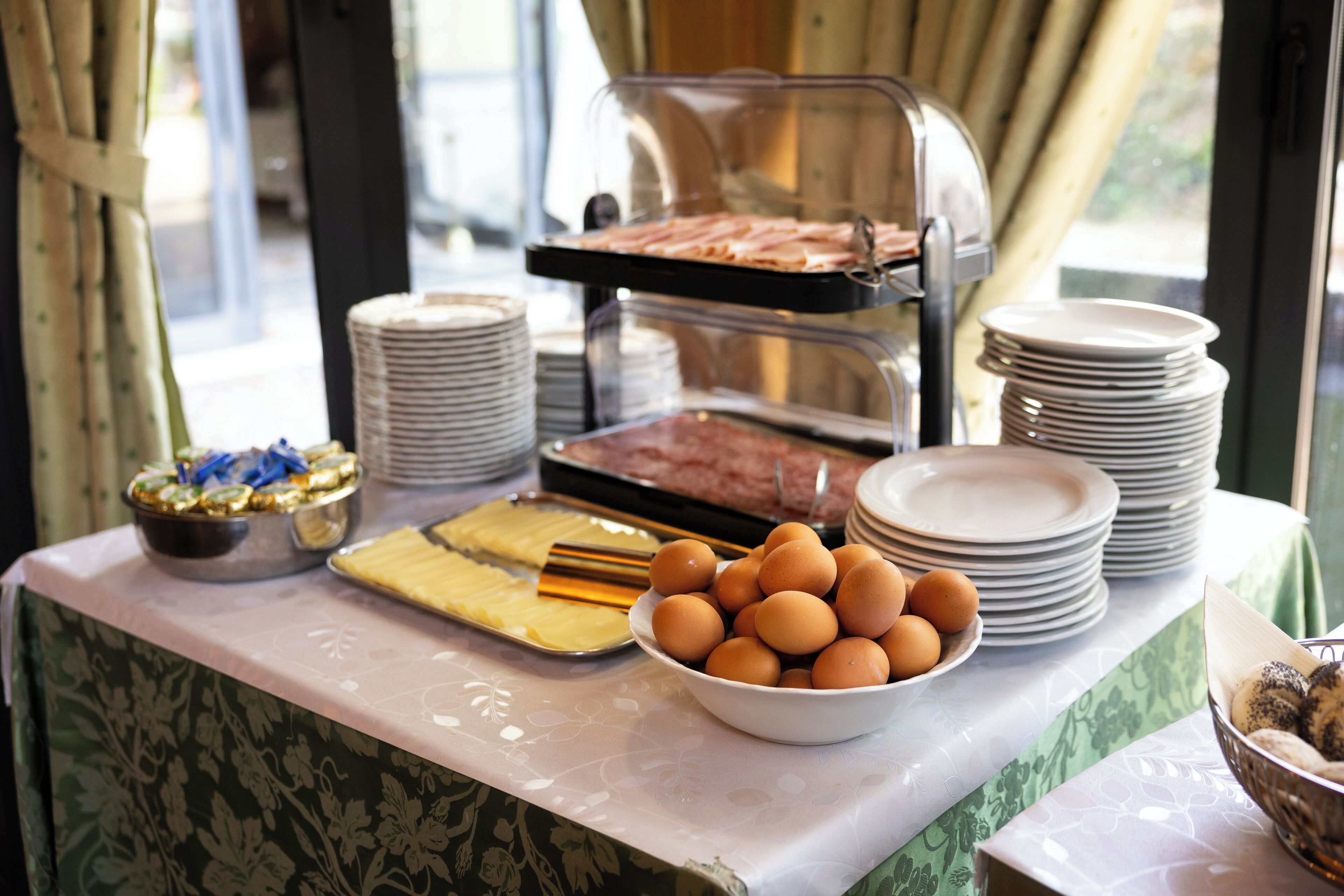 Een buffetopstelling met diverse gerechten en stapels borden.