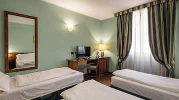 Een hotelkamer met twee enkele bedden, een bureau met een televisie, een stoel, een lamp en een grote spiegel.
