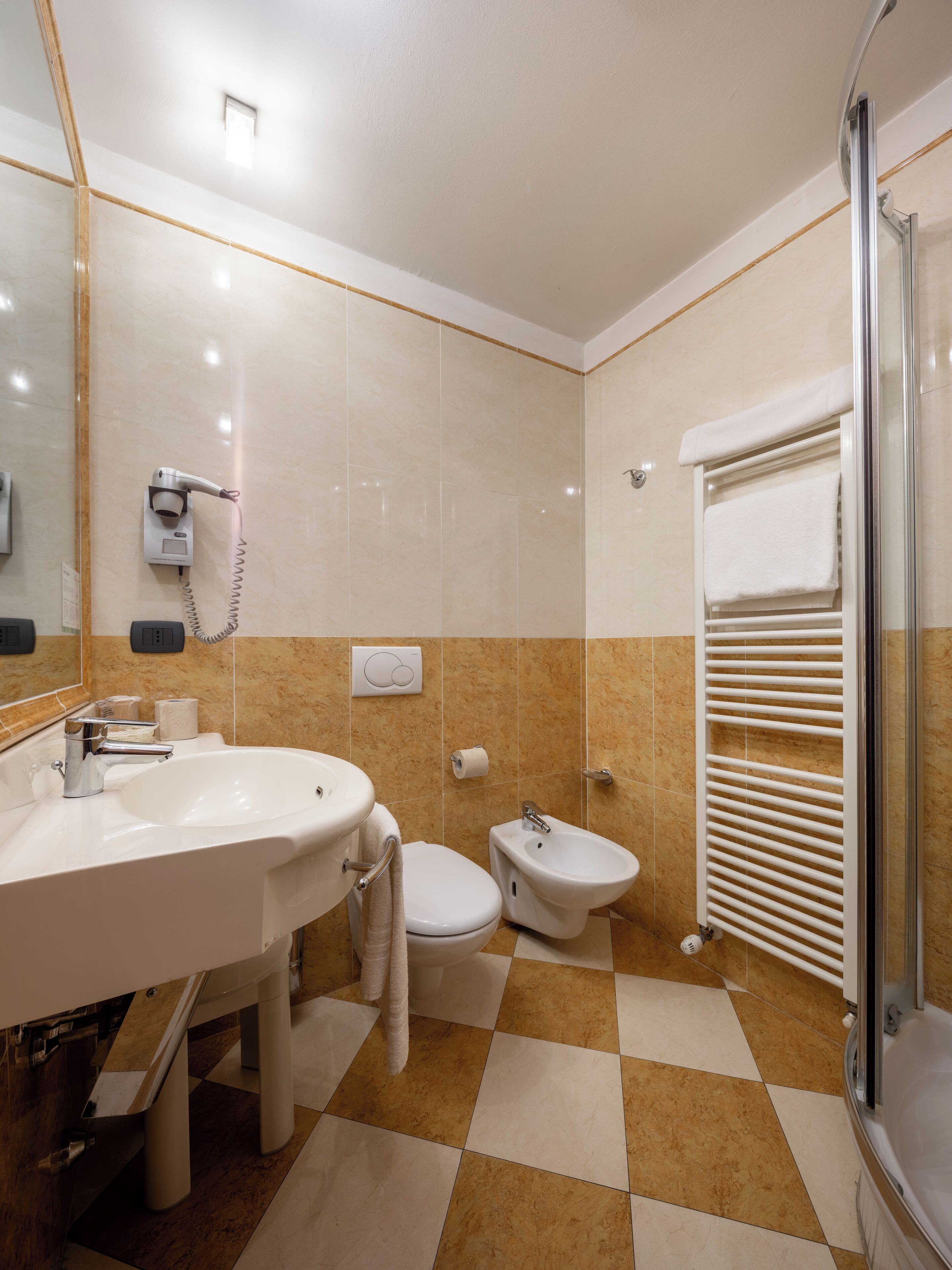 A bathroom with a sink, toilet, bidet, and a shower area.
