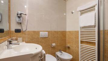 Ein Badezimmer mit Waschbecken, Toilette, Bidet und Duschbereich.