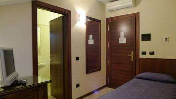 Una habitación de hotel con una cama, un escritorio con televisor y dos puertas.