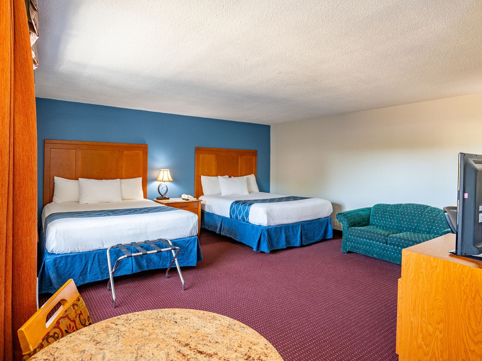 Une chambre d’hôtel avec deux lits, un bureau, une chaise et un téléviseur.
