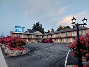 A Huntsville Inn motel with a two-story structure, a parking lot, and a red vehicle parked in front. - Huntsville Inn (Huntsville)