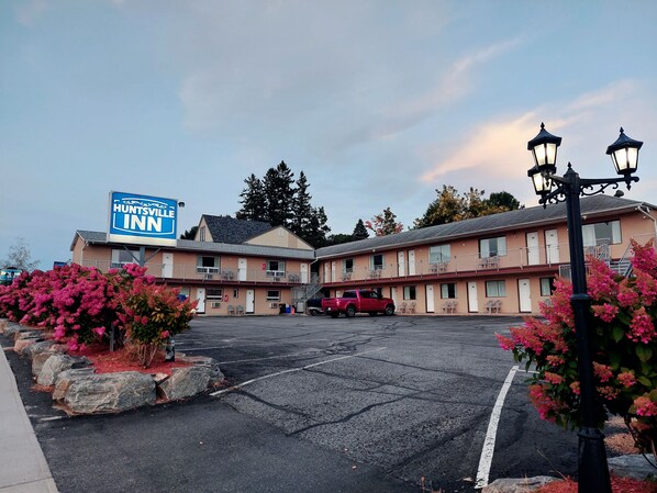 A Huntsville Inn motel with a two-story structure, a parking lot, and a red vehicle parked in front. - Huntsville Inn (Huntsville)