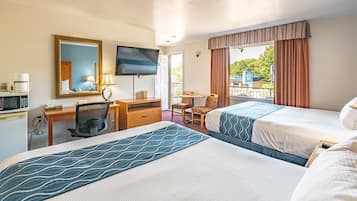 A hotel room with two beds, a desk with a chair, a television, and a window with curtains.