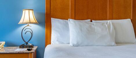 A hotel room with a bed, a nightstand with a lamp, and a telephone.