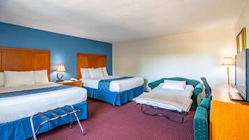A hotel room with two beds, a desk, a television, and a wheelchair.