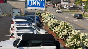A parking lot with several cars, a sign for Huntsville Inn, and a building with a sign for Muskogee Auto Parts. - Huntsville Inn (Huntsville)