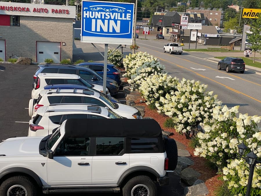 A parking lot with several cars, a sign for Huntsville Inn, and a building with a sign for Muskogee Auto Parts.